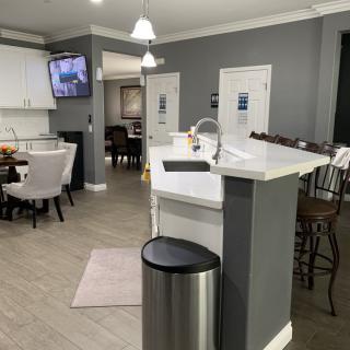 A modern kitchen with an open layout featuring a central island, bar stools, and pendant lighting.