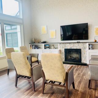 A modern living room with a fireplace and television, featuring comfortable seating and stylish decor.