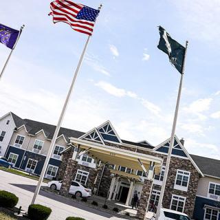 A building with multiple flags displayed at the entrance under a clear sky.
