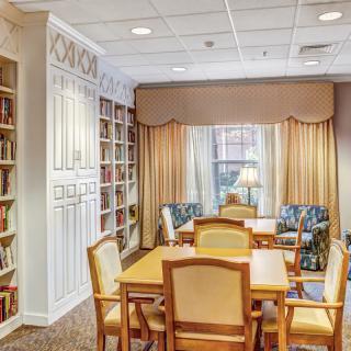 A cozy library reading room with bookshelves, a table, and chairs.