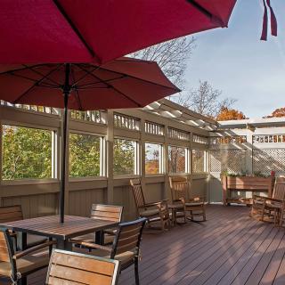 A spacious outdoor patio with wooden furniture and large red umbrellas.