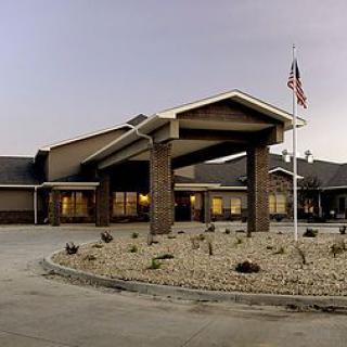 A building with an American flag at dusk, featuring a landscaped entrance.