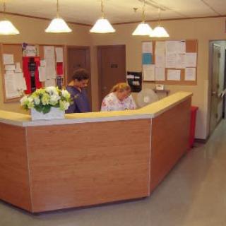 A reception desk area with two people working behind the counter.
