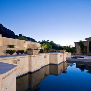 A luxurious modern home with a serene outdoor pool reflecting the clear evening sky.