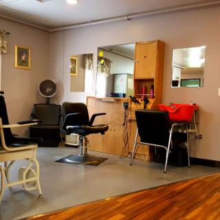 A cozy hair salon interior with chairs, mirrors, and equipment.