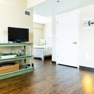 A cozy living space featuring a television on a green shelf, with a view into the adjacent bedroom.