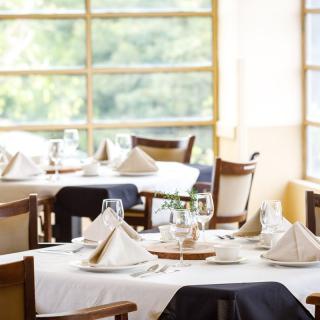 A well-appointed dining room with neatly set tables and chairs, featuring elegantly folded napkins and glassware.