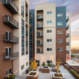 A modern apartment building with balconies and a spacious outdoor area at sunset.