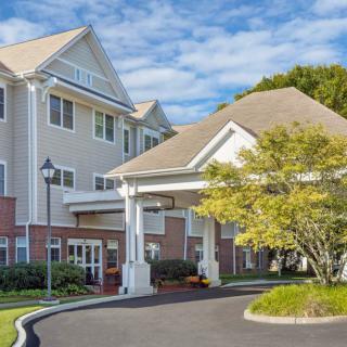 A scenic view of a residential building entrance surrounded by greenery on a clear day.