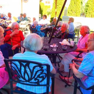 A group of seniors enjoying a social gathering on a sunny patio.