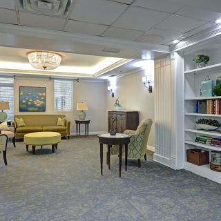 A well-furnished living room featuring a sofa, armchairs, and decorative bookshelves.