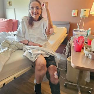 A patient recovering in a hospital bed, smiling and showing a positive attitude after knee surgery.