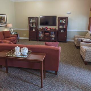 A cozy living room with sofas, a television, and decorative shelves.
