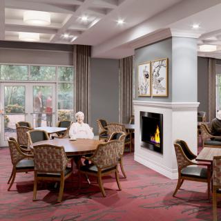 A cozy dining area with wooden furniture, a fireplace, and large windows providing natural light.