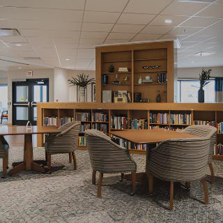 A quiet and cozy library space with bookshelves, tables, and chairs for reading.