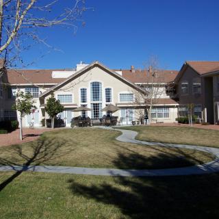 A residential building with a well-maintained lawn and clear blue skies.