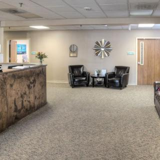 A spacious and well-decorated reception area with seating and a large clock on the wall.