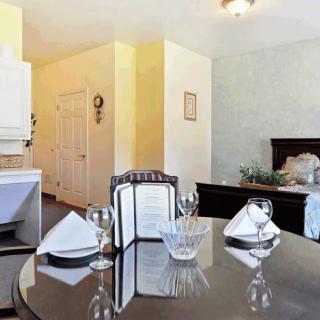 A cozy home interior with a set dining table and a view of the kitchen and bedroom.