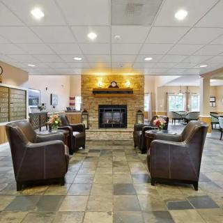 A modern lobby with leather chairs and a central fireplace.