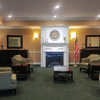 A warmly lit lobby with a comfortable seating area, featuring a fireplace and an American flag.