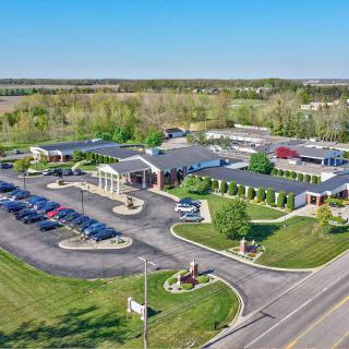 Aerial view of a large building with a parking lot and surrounding greenery.