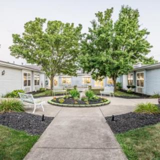 A neatly landscaped courtyard with benches, surrounded by buildings and trees.