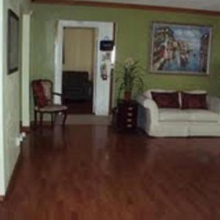 A cozy living room with hardwood flooring, featuring a sofa, an armchair, and decorative artwork on the wall.