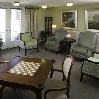 A cozy living room with traditional decor featuring comfortable chairs and a table set for games or social gatherings.