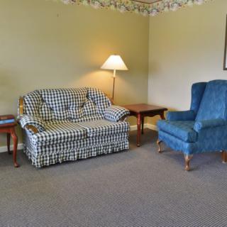 A cozy living room with a patterned sofa, blue armchair, and a floor lamp.