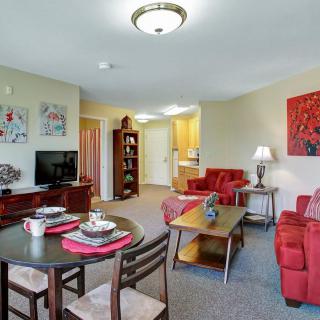 A cozy living room with red furniture and a small dining area.