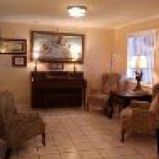 A cozy living room featuring a piano, comfortable chairs, and a warm lighting ambiance.