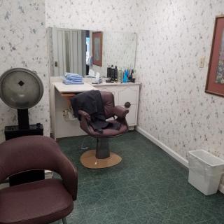 A small hair salon with a styling chair, mirror, and hair dryer.