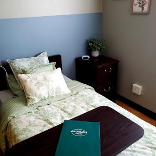 A cozy bedroom setup featuring a neatly made bed with green bedding and decorative pillows.