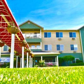 A three-story building with a well-maintained lawn under a clear blue sky.