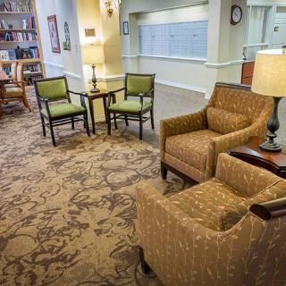 A cozy seating area in a lobby with chairs and lamps, featuring elegant carpet and interior design.