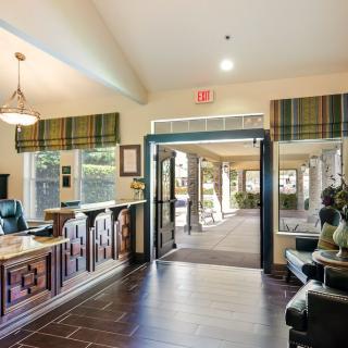 A warmly decorated lobby with a reception desk and large windows leading to an entrance.