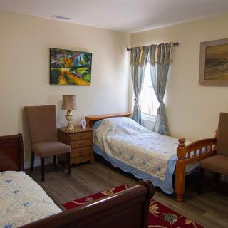 A cozy bedroom with two single beds, chairs, and decorative wall art.