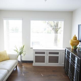 A modern and minimalist living room with a white sofa, decorative elements, and large windows.