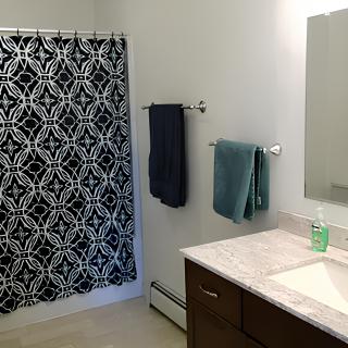 A modern bathroom with a patterned shower curtain and neatly arranged towels.