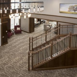 Spacious lobby with a wooden staircase and elegant chandeliers.
