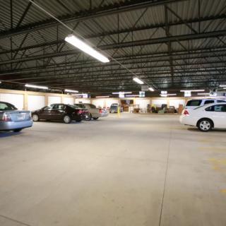An indoor parking garage with several parked cars and overhead lighting.