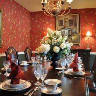A beautifully set dining room table with an elegant floral centerpiece and rich wallpaper.