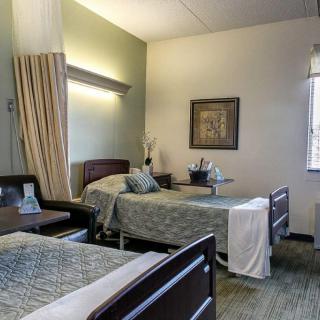 A hospital room with two beds separated by a privacy curtain, featuring simple and clean interior decor.