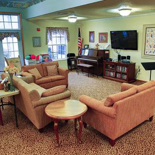 A cozy living room with sofas, a piano, and a television.