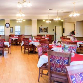 A well-decorated dining room with arranged tables and chairs, featuring warm lighting.