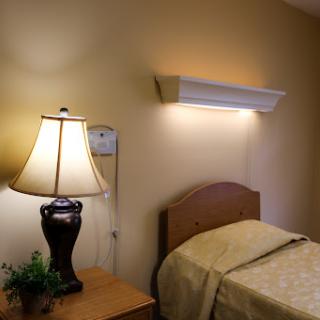 A cozy bedroom setup featuring a lamp, bed, and decorative elements.