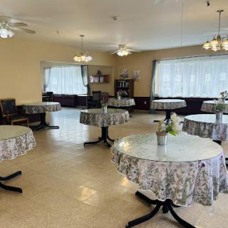 A spacious and well-lit dining area featuring tables adorned with floral tablecloths, ready for guests.
