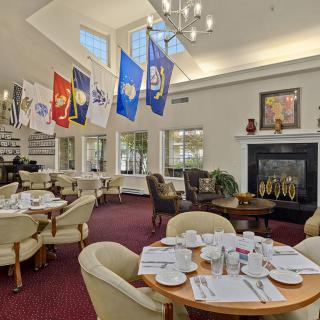 A well-appointed dining room with multiple flags, elegant tables and chairs, a fireplace, and a chandelier.