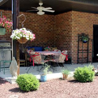 A cozy outdoor patio area decorated with flowers and equipped with comfortable furniture.