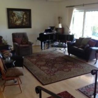 A well-furnished living room with a piano and various seating options.